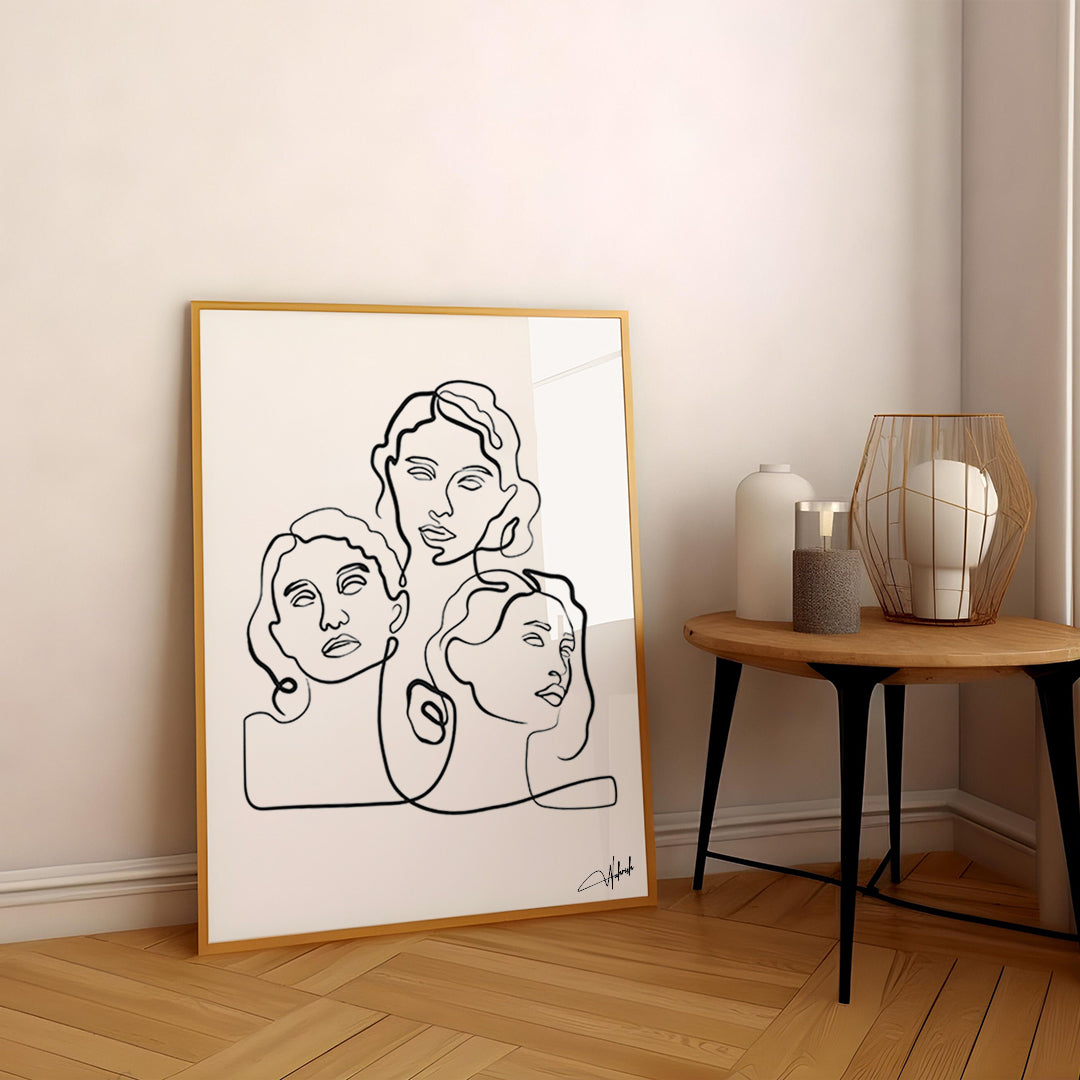 Minimal line art of three abstract female faces framed on a bright interior wall


